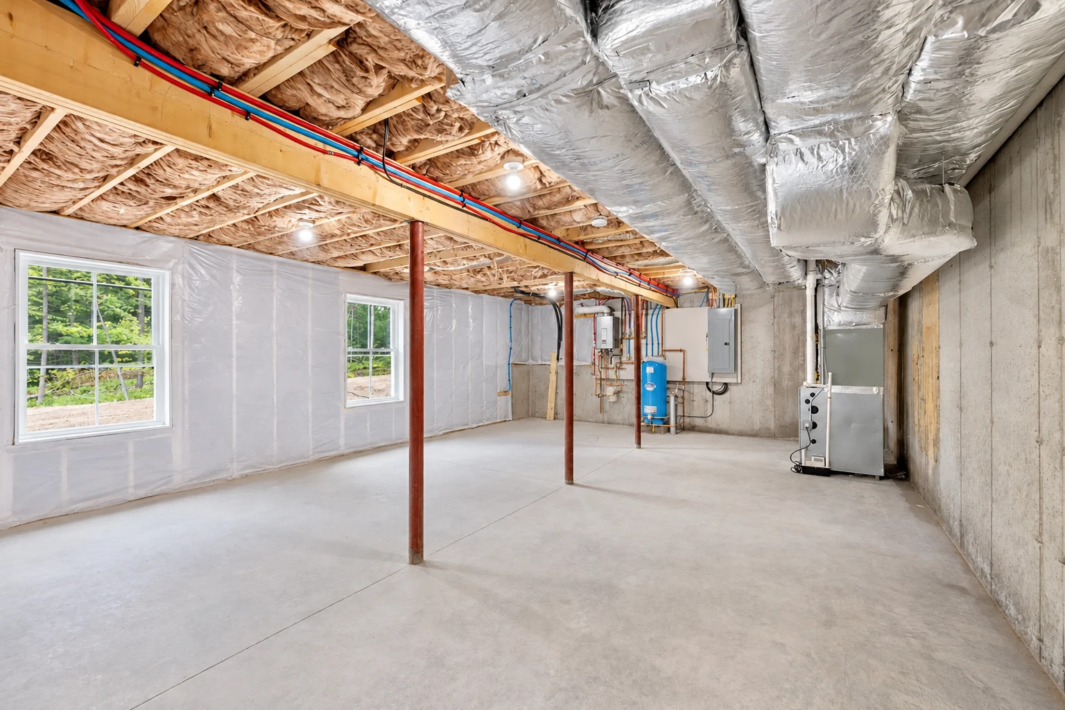 Unfinished basement with foil-wrapped ductwork overhead, insulated ceiling joists, plastic-covered walls, and exposed utilities.